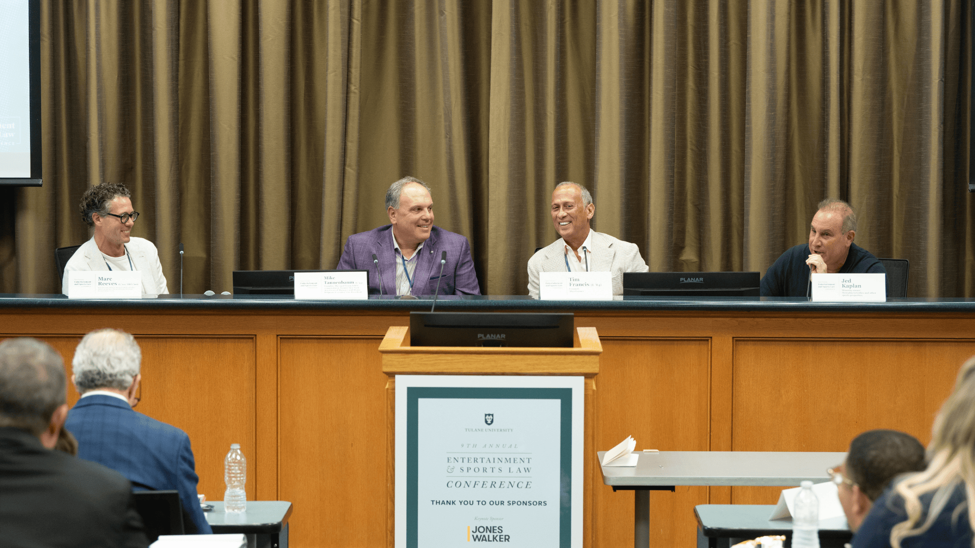 Four speakers sit at a table during a panel.