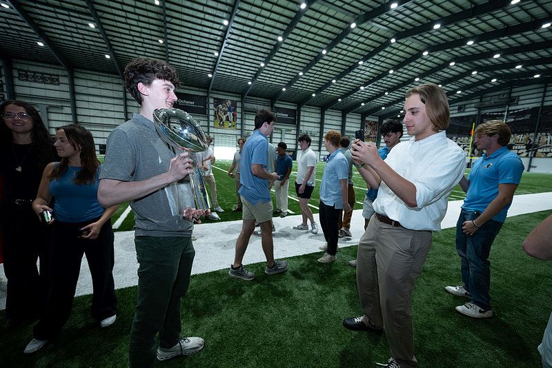 Students posing with NFL trophy at Sports Institute