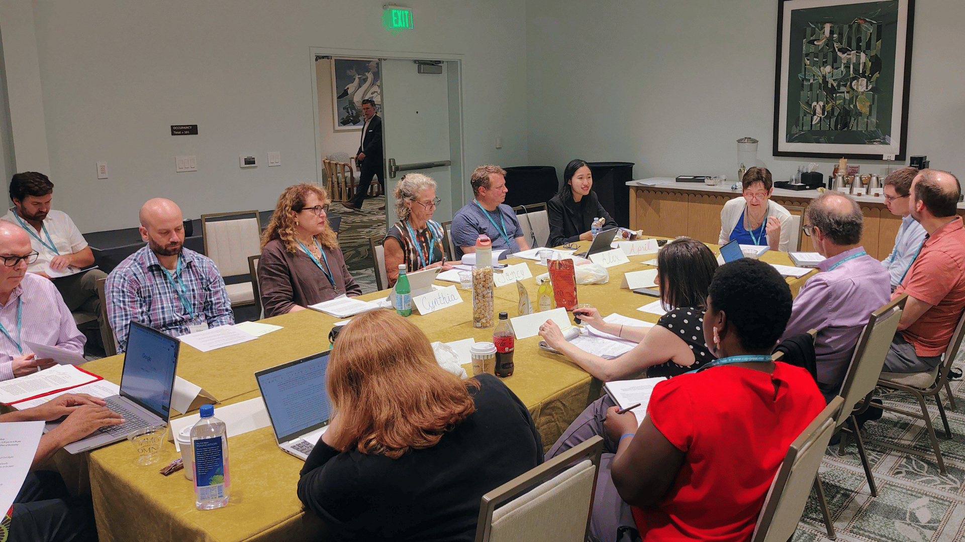 Diverse group of people sitting around a large conference table during a meeting.