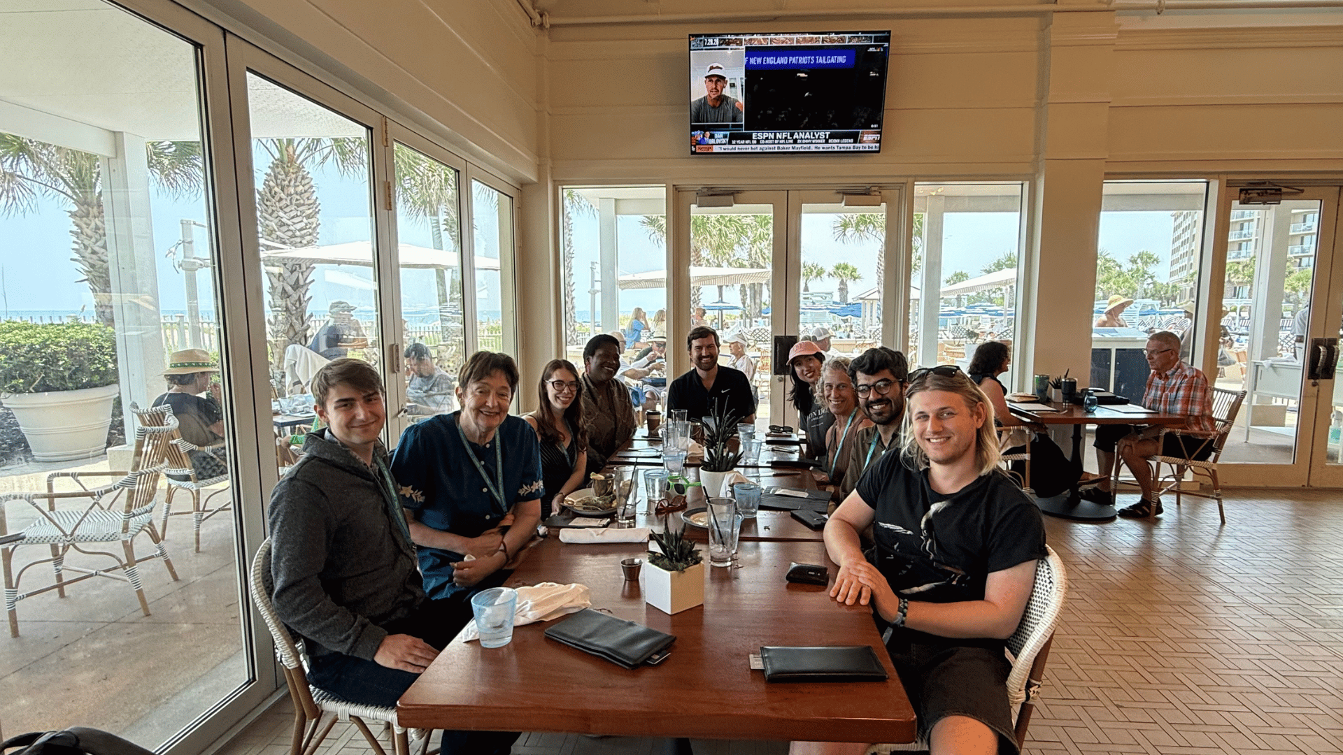 A group of individuals smile for a photo while sitting at a table in a restaurant.