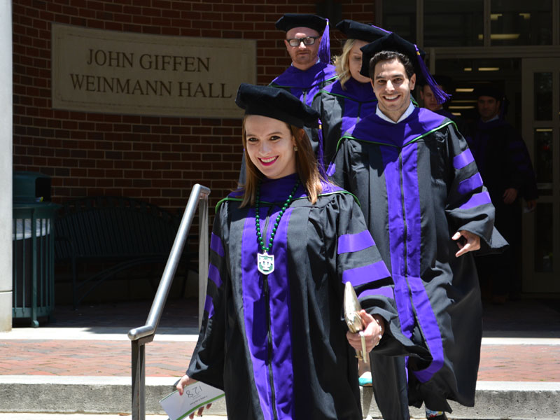 Law graduates in regalia exiting Weinmann Hall