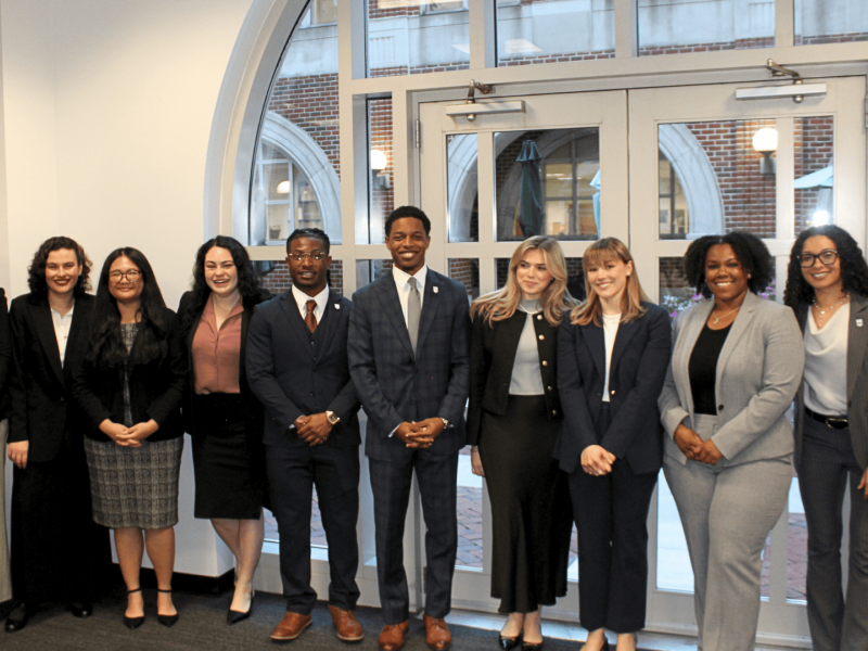 Ten diverse professionals, men and women, smiling in a modern building.