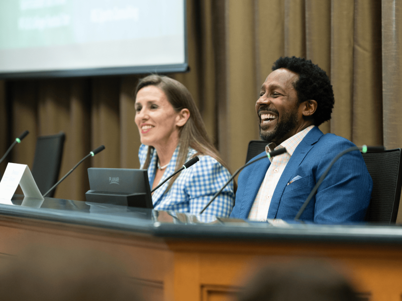 Desmond Howard and Renee Gomila smiling at a panel discussion.