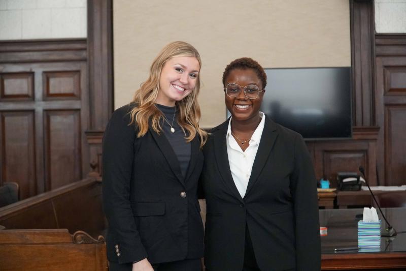 Two Law students smiling in a court room. Two Law students smiling in a court room.