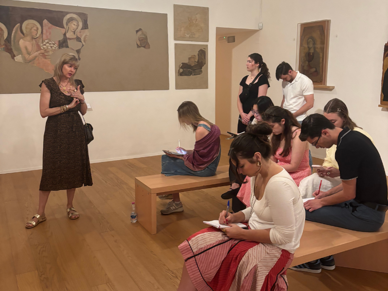 Students sit and take notes in an art gallery.