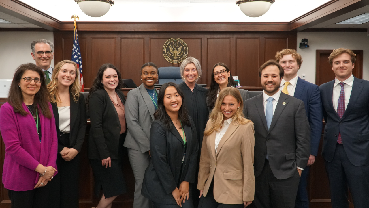 Law students pose for a photo with a judge in a courtroom.