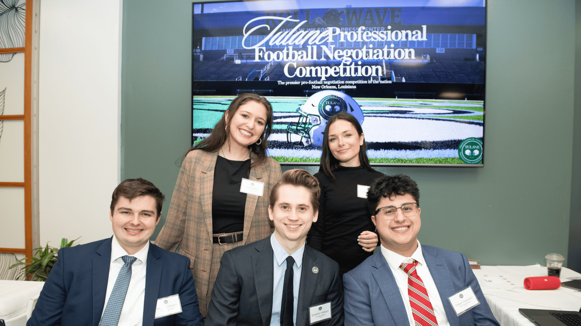 Students pose for a photo in front of a sign that reads "Tulane Professional Football Negotiation Competition"