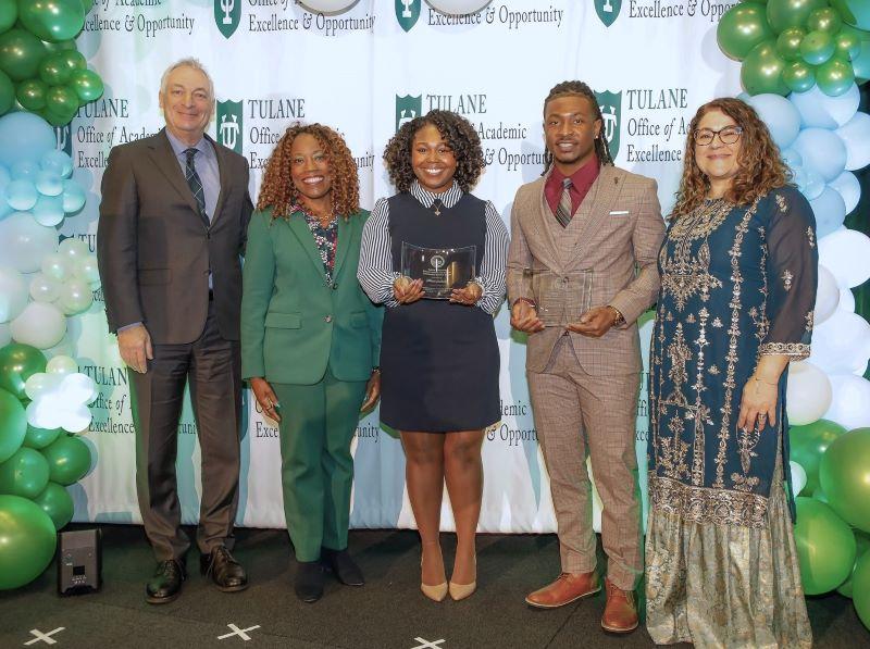 Five people, including two holding awards, pose at a Tulane Office of Academic Excellence & Opportunity event with balloons.