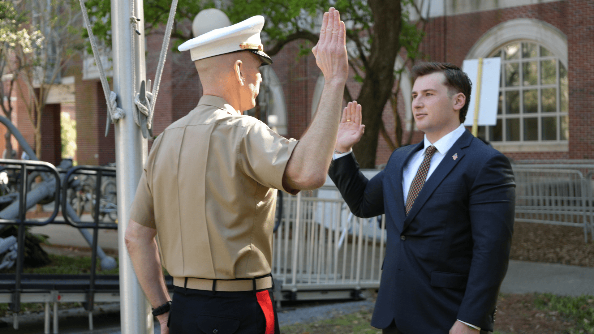 Officer in Marine uniform swears in a man wearing a suit.