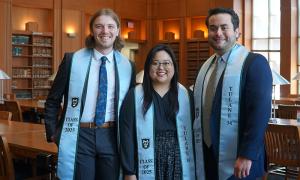 Jack Dean, Katie Chong, and Pablo Gonzales pose for a photo in the Law Library. They wear blue and green stoles that read "Tulane 34" and "Class of 2025"