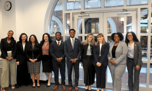 Ten diverse professionals, men and women, smiling in a modern building.